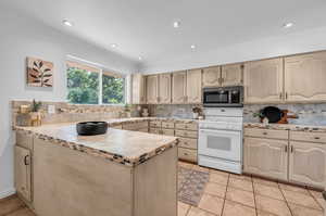 Kitchen with decorative backsplash, light brown cabinetry, light tile patterned floors, and white range oven