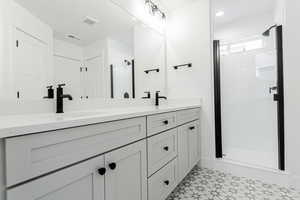 Bathroom featuring tile patterned floors, vanity, and walk in shower