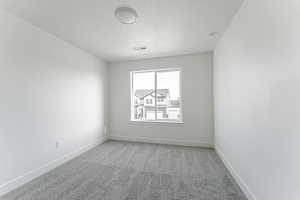 Carpeted empty room with a textured ceiling