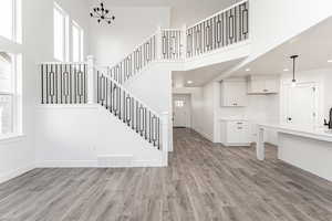 Staircase featuring a chandelier, wood-type flooring, and a towering ceiling