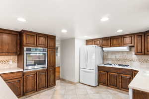 Kitchen featuring light wood-type flooring, white appliances, and backsplash