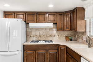 Kitchen featuring sink, tasteful backsplash, and white appliances