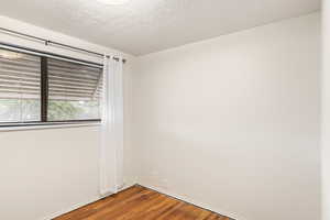 Empty room featuring a textured ceiling and wood-type flooring