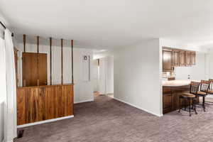 Kitchen featuring a kitchen breakfast bar, dark colored carpet, and kitchen peninsula