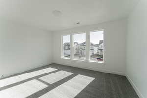 Spare room featuring dark colored carpet