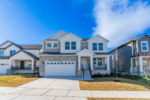 View of front of property with a garage, covered porch, and a front lawn