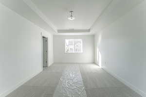 Carpeted empty room featuring a tray ceiling