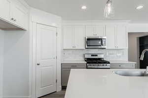 Kitchen with pendant lighting, white cabinets, and stainless steel appliances