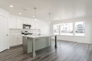 Kitchen featuring white cabinets, dark hardwood / wood-style floors, a kitchen island with sink, and white range with gas cooktop