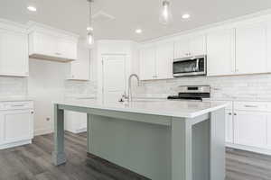 Kitchen with appliances with stainless steel finishes, hardwood / wood-style flooring, pendant lighting, and sink