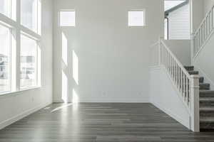 Unfurnished living room featuring a towering ceiling and dark hardwood / wood-style floors