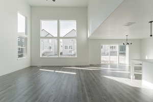 Unfurnished living room featuring a towering ceiling, wood-type flooring, and a notable chandelier