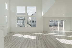 Unfurnished living room with a wealth of natural light, light hardwood / wood-style flooring, and a high ceiling