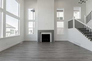 Unfurnished living room with a fireplace, dark wood-type flooring, and a high ceiling