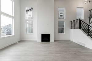 Unfurnished living room with a wealth of natural light, light hardwood / wood-style flooring, and a chandelier