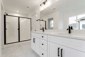 Bathroom with a shower with door, vanity, and a healthy amount of sunlight