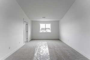 Empty room with light carpet and vaulted ceiling