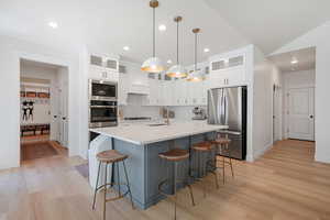 Kitchen featuring sink, hanging light fixtures, stainless steel appliances, tasteful backsplash, and a kitchen island with sink