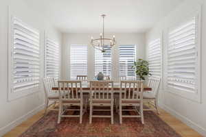 Dining room featuring wood-type flooring, a notable chandelier, and a healthy amount of sunlight