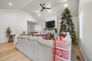 Living room with hardwood / wood-style floors, ceiling fan, and high vaulted ceiling