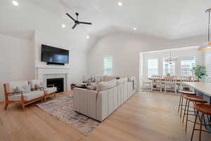 Living room featuring a fireplace, light wood-type flooring, plenty of natural light, and lofted ceiling