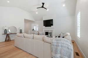 Living room featuring ceiling fan, light wood-type flooring, and vaulted ceiling