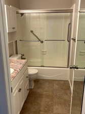 Full bathroom featuring tile flooring, bath /shower combo with glass door, toilet, and vanity