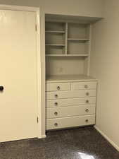 Features closet, storage and built-shelving and drawers, carpeted floor.