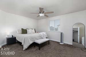 Bedroom featuring dark carpet, a walk in closet, ceiling fan, and a closet