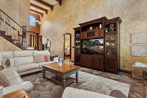 Tiled living room featuring a chandelier, a towering ceiling, and beam ceiling