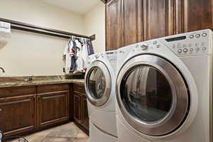 Laundry room with light tile patterned flooring, cabinets, and independent washer and dryer