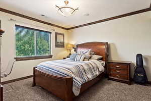 Bedroom with ornamental molding and carpet