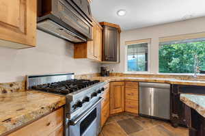 Kitchen featuring sink, appliances with stainless steel finishes, custom exhaust hood, and dark tile patterned flooring