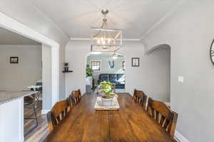 Dining room with ceiling fan with notable chandelier, crown molding