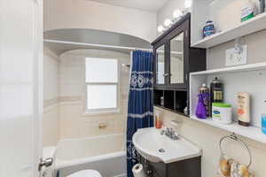 Bathroom with vanity, shower / tub combo, and tile walls