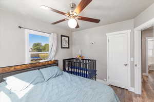 Bedroom with ceiling fan, dark hardwood / wood-style flooring, and connected bathroom