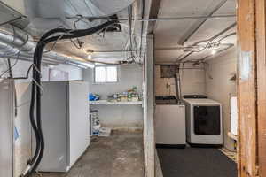 Basement with washer and clothes dryer and white fridge