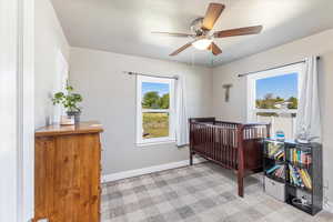 Carpeted bedroom with a nursery area and ceiling fan