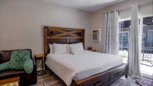 Bedroom with dark hardwood / wood-style floors, multiple windows, and a wall mounted AC