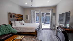 Bedroom with access to exterior, dark wood-type flooring, and an AC wall unit