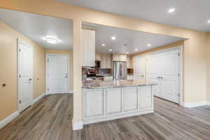 Kitchen featuring kitchen peninsula, appliances with stainless steel finishes, light wood-type flooring, light stone counters, and sink