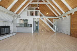 Unfurnished living room featuring wooden ceiling, high vaulted ceiling, beam ceiling, and light wood-type flooring