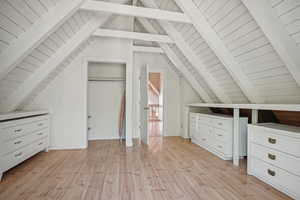 Additional living space featuring light hardwood / wood-style floors and lofted ceiling with beams