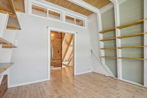 Interior space featuring beamed ceiling, wood walls, wood ceiling, and light wood-type flooring