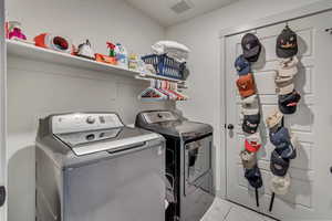 Washroom with washer and dryer and light tile patterned floors