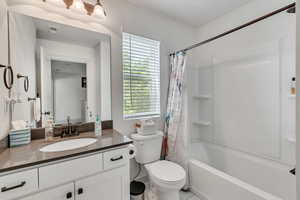 Full bathroom featuring shower / bath combo with shower curtain, vanity, tile patterned flooring, and toilet