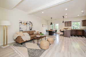 Living room featuring beamed ceiling, light hardwood / wood-style floors, and plenty of natural light