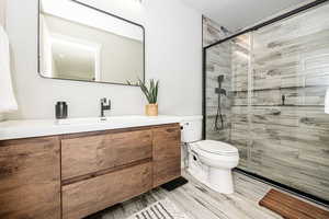 Bathroom featuring vanity, walk in shower, and toilet