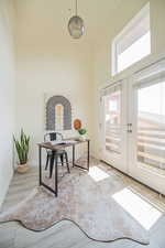 Office area featuring light wood-type flooring, french doors, and a towering ceiling