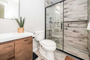 Bathroom with vanity, toilet, and an enclosed shower